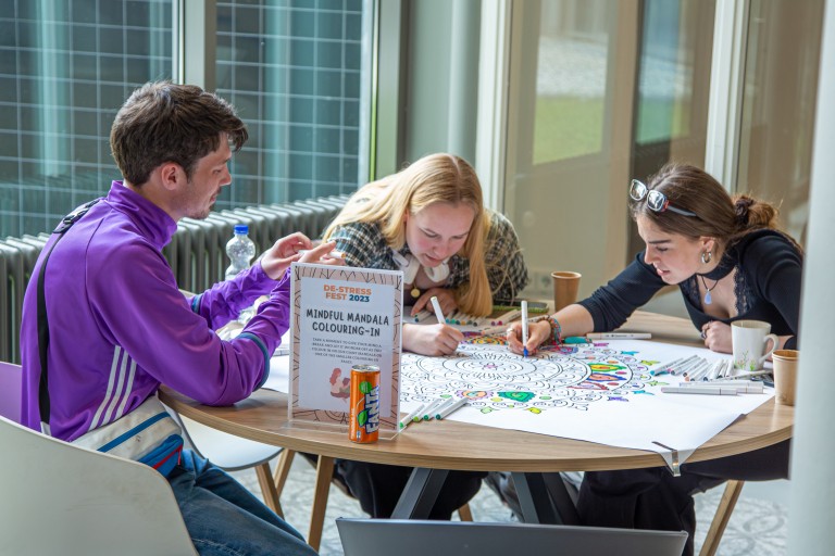 Drie studenten kleuren een mandela in