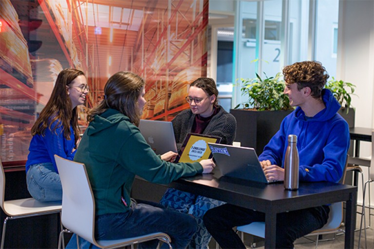 Vier studenten werken met hun laptop aan een tafel