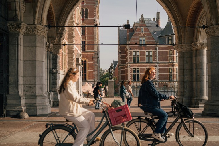 Twee meisjes fietsen langs het Rijksmuseum