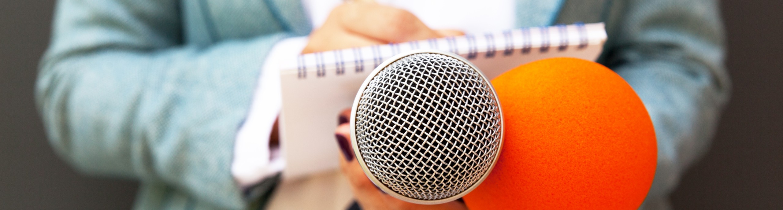 Iemand met een microfoon en notitieblok