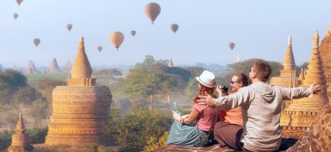 Drie toeristen kijken naar een lucht vol luchtballonnen